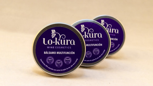 Bálsamo multifunción lo-kura wine cosmetics, tres latas de aluminio con etiqueta morada. primer plano de una de ellas