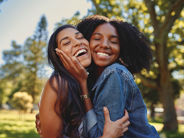 Two women embracing joyfully outdoors