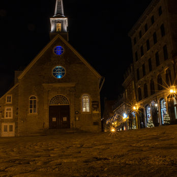 A small church at night on a cobble stone courtyard in Quebec city.