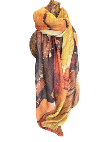 Golden and amber silk scarf with sun-inspired abstract patterns, draped on a mannequin.