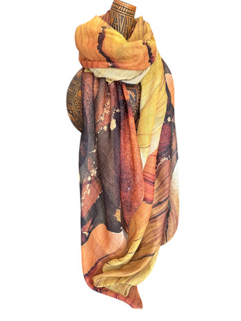 Golden and amber silk scarf with sun-inspired abstract patterns, draped on a mannequin.