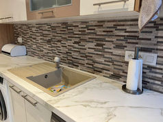 Cuisine rénovée avec une crédence en mosaïque et un plan de travail élégant.