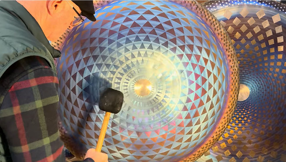 Brry Mason using a mallet on a titanium gong with sacred geometric patterns