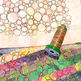 Colour fabric scraps, free motion embroidery and an Aurifil 40wt thread spool on top