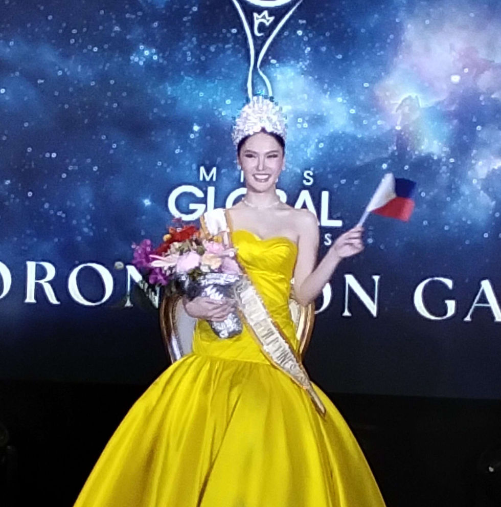 Jayvee Lyn Lorejo in a bright yellow gown and crown smiles, holding flowers and a small flag of the Philippines