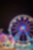A lit-up ferris wheel with a merry-go-round at the carnival area of Winter Fest OC.