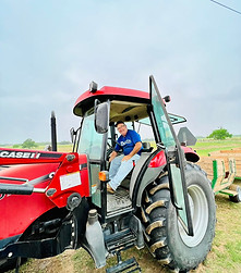 A Rockberry Ranch tractor driver smiling while he drives a large red tractor.