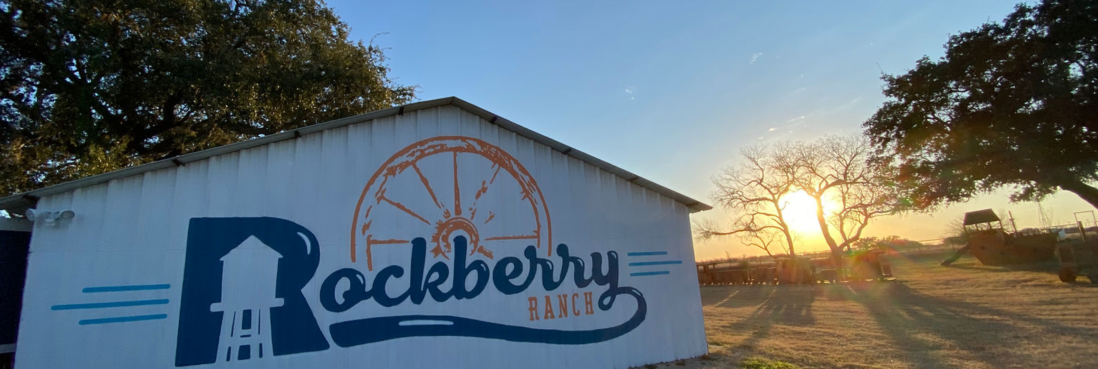The Rockberry Ranch logo mural on the side of a barn at sunset.