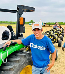A Rockberry Ranch attractions operator posing with the tractor that drives the Bee Train.