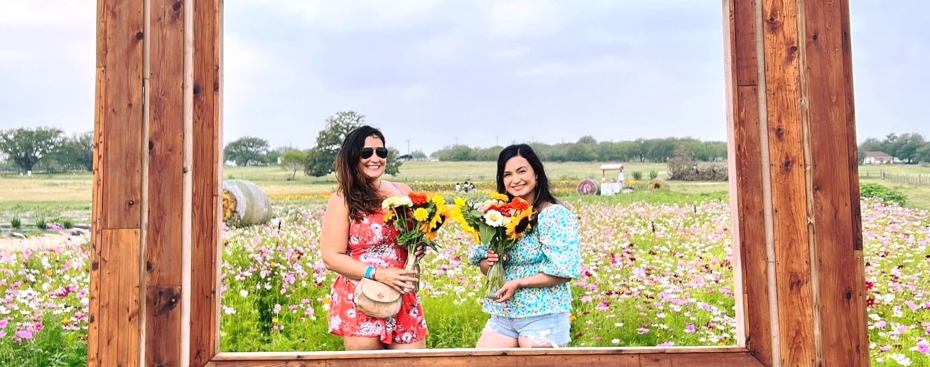 Two women posing in a giant frame photo op at Rockberry Ranch flower farm.