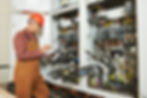 adult electrician builder engineer worker with electric scheme plan in front of fuse switch board