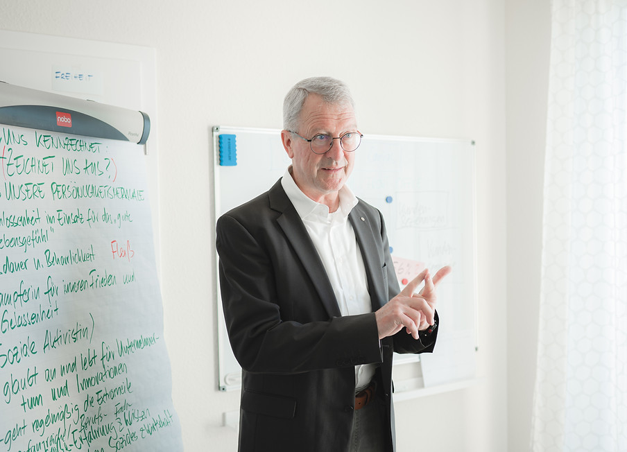 Ein Mann steht vor einem Whiteboard und hält einen Vortrag