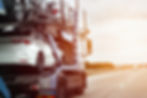 A tow truck carries a car on a flatbed trailer on the highway, providing transport service