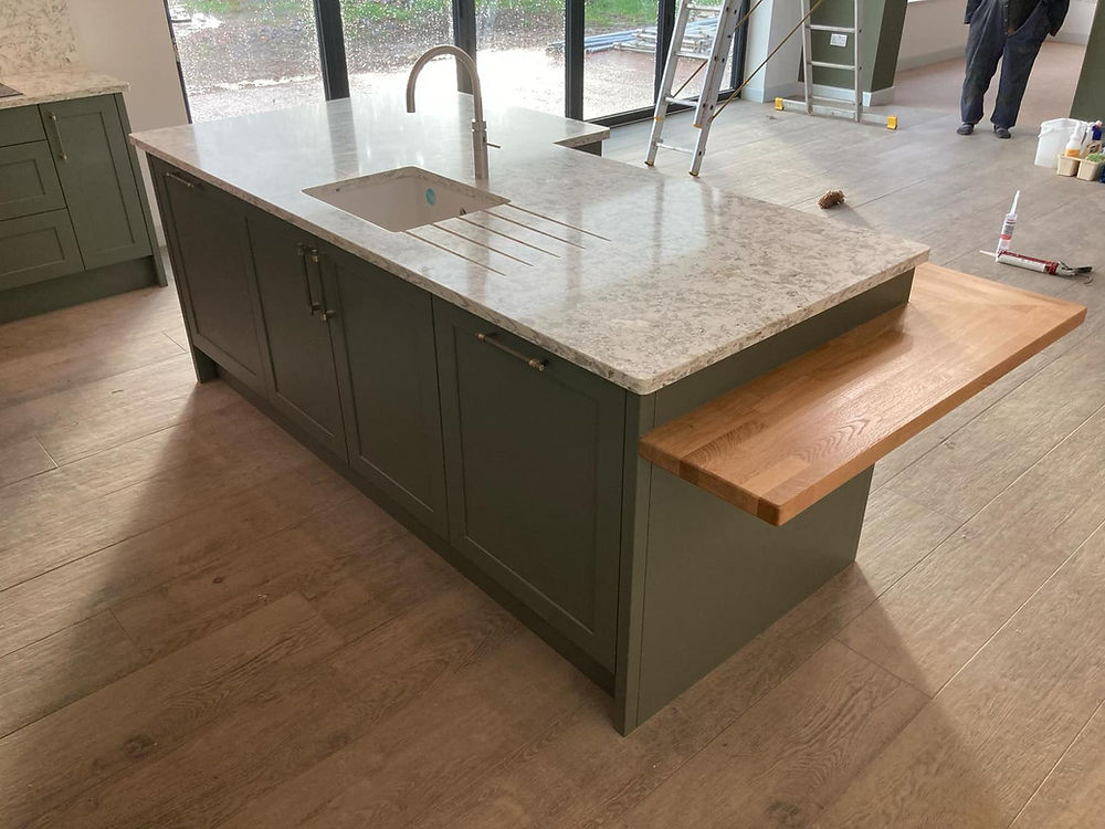 Modern kitchen island featuring granite and wood worktops.