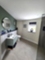 Modern bathrooms in Ilminster with green walls and round mirror.