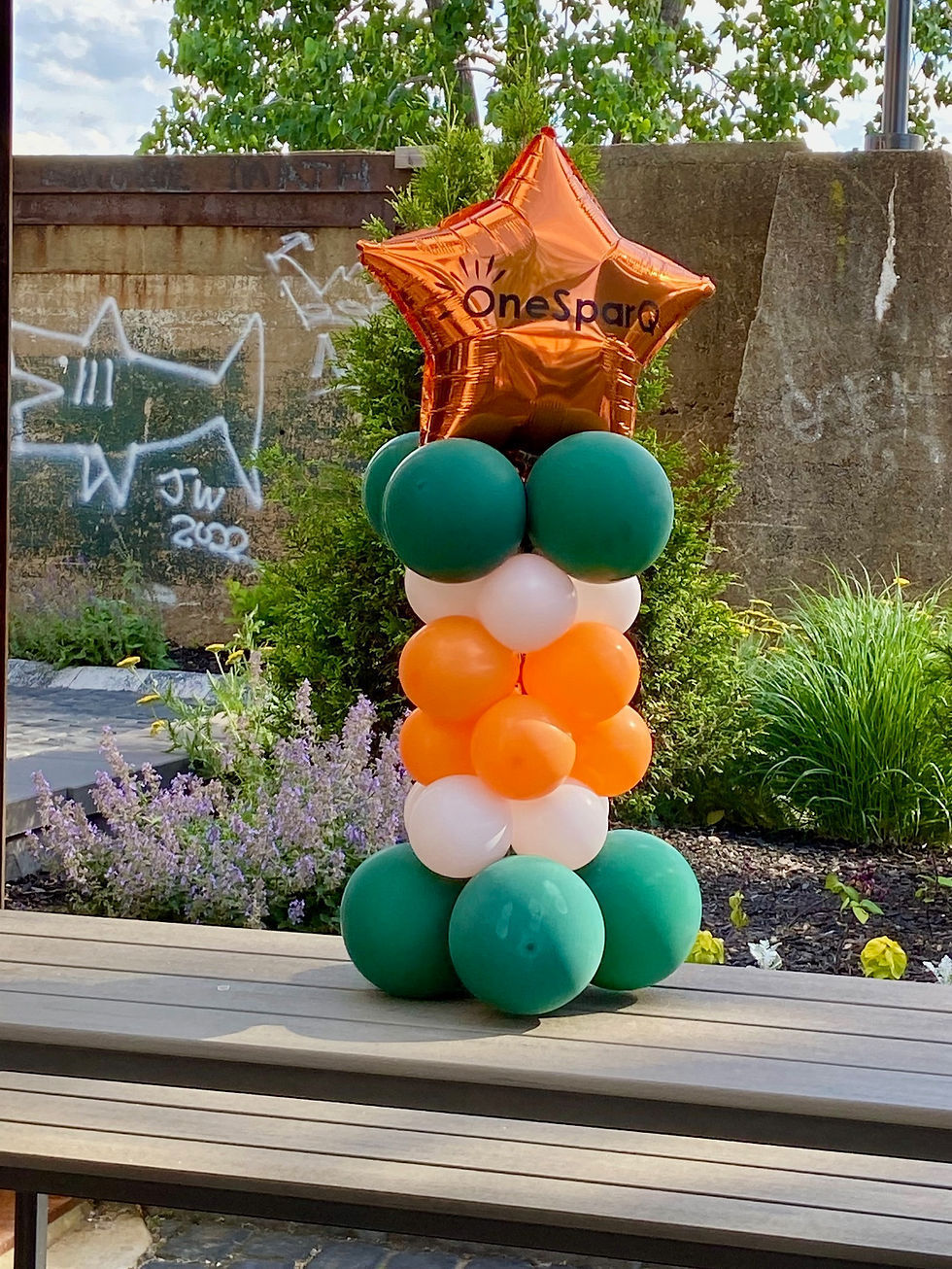 Thumbnail: Small balloon pillar. Green, orange and white colors. Mylar balloon saying "OneSparQ" on top