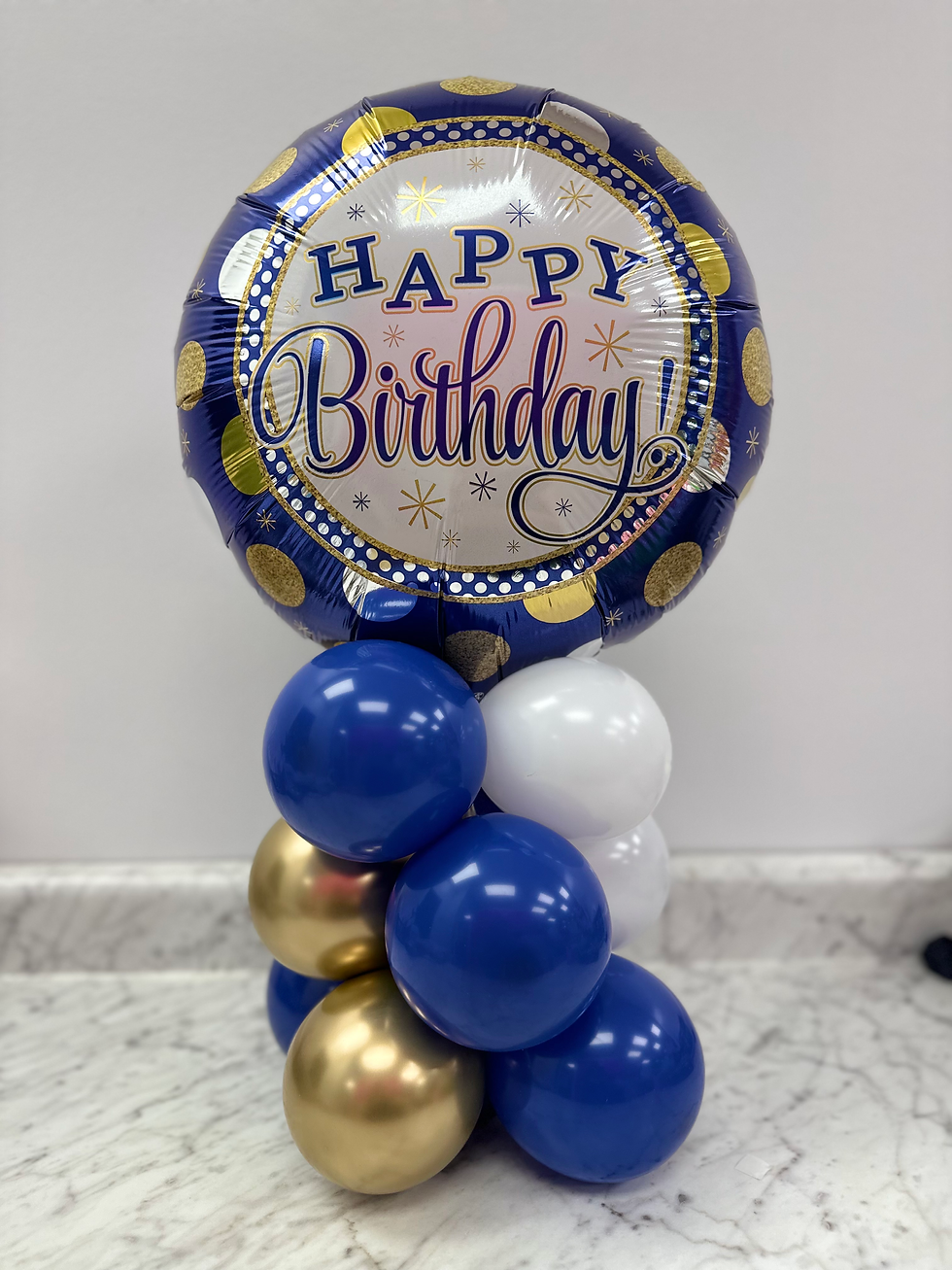 Thumbnail: Small balloon pillar. Blue, gold and white colors. Mylar balloon saying "happy birthday" on top