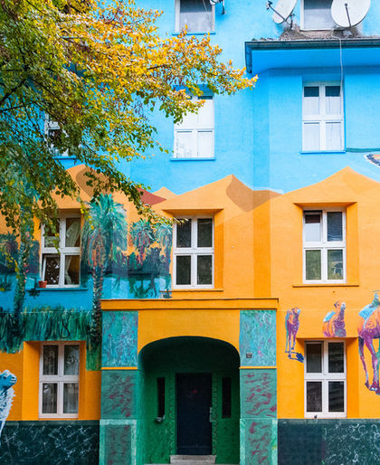 Die fertig bemalte Fassade der Kiefernstraße 12 mit Kamelkarawane, Wüstenlandschaft, Tieren und dem grünen Hauseingang.