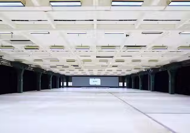 Leere, weitläufige Industriehalle im NLND mit markanter Deckenstruktur und Säulenreihen.