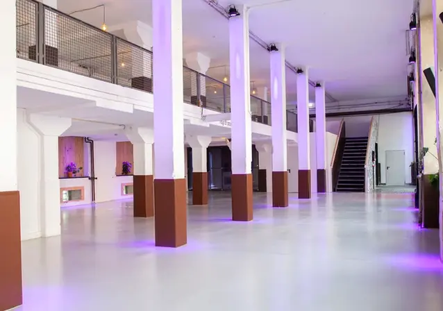 Historische Säulenhalle mit moderner lila Beleuchtung und industriellen Details.