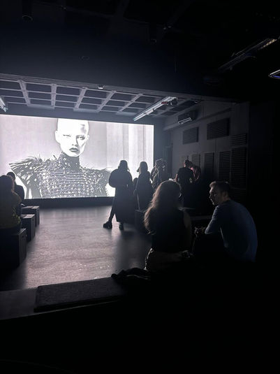 Besucher der KI-Kunstausstellung "Contract of Fiction" im P61 in Berlin, blicken auf ein digitales Kunstwerk in schwarz-weiß.