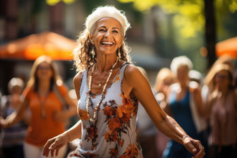 authentic branding expressed Smiling woman with curly hair dancing outdoors in floral dress, with blurred people and orange umbrellas in the sunny background.