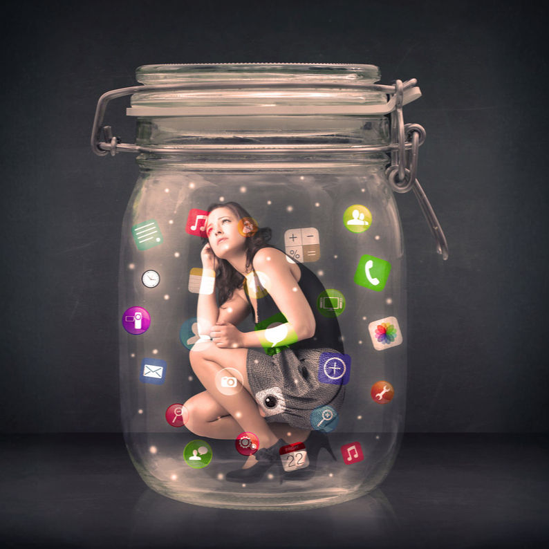 Woman crouching inside a glass jar surrounded by colorful app icons on a dark background, suggesting digital overload.