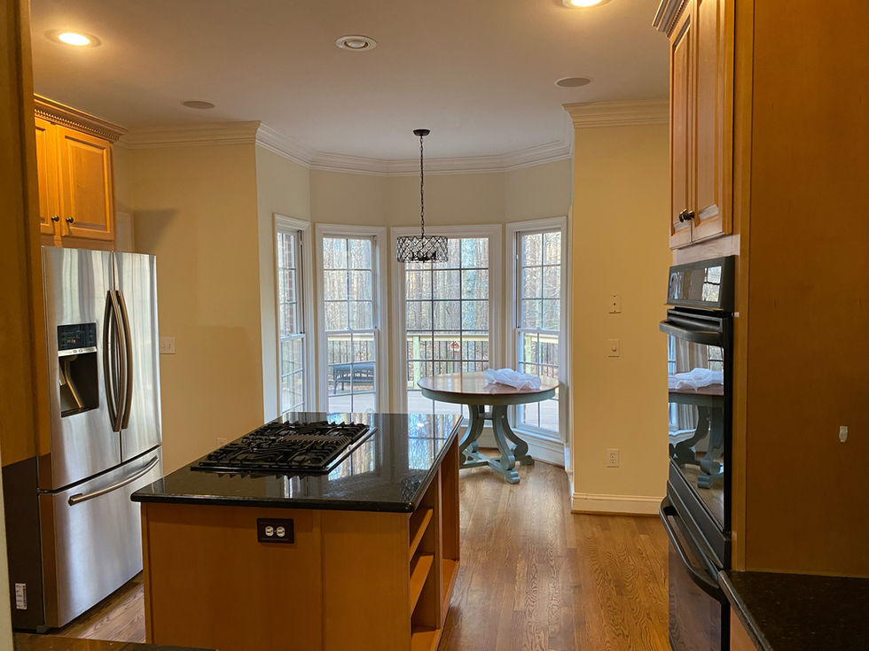 Kitchen with island, stainless steel fridge, and windows showing Carriage Crossing ESC Cabinets.