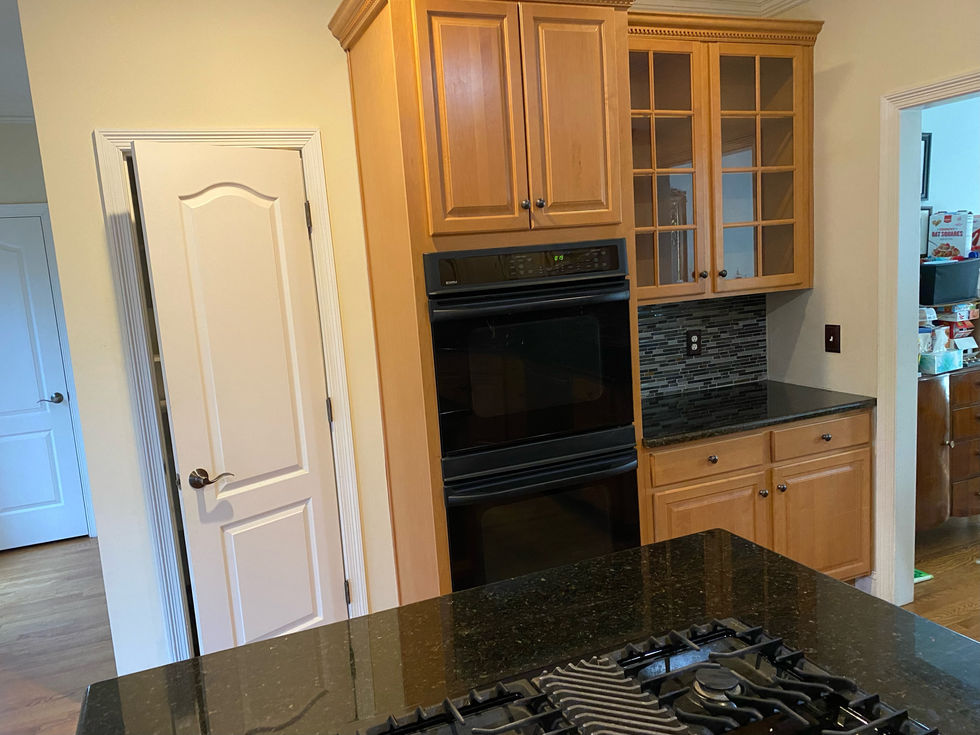 Kitchen with cabinets, oven, and black countertop; ESC Cabinets in the home.