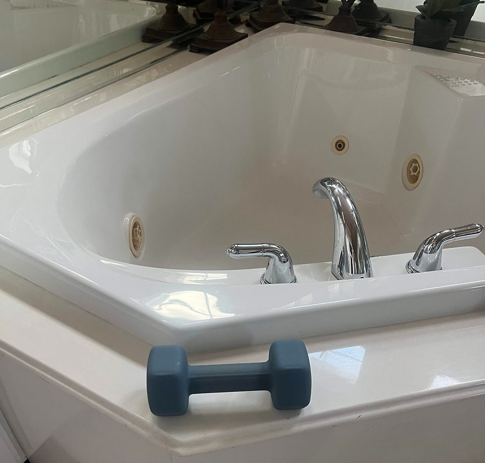A blue dumbbell rests on the edge of a white corner bathtub with chrome fixtures.