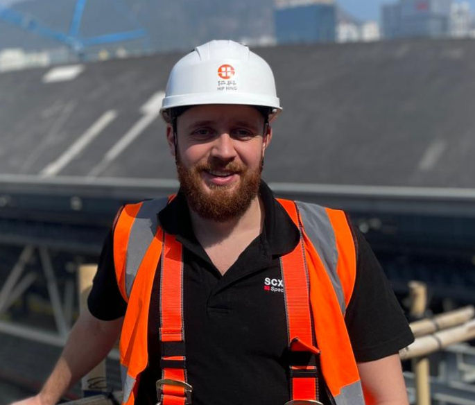 Man in hard hat, safety vest on construction site.