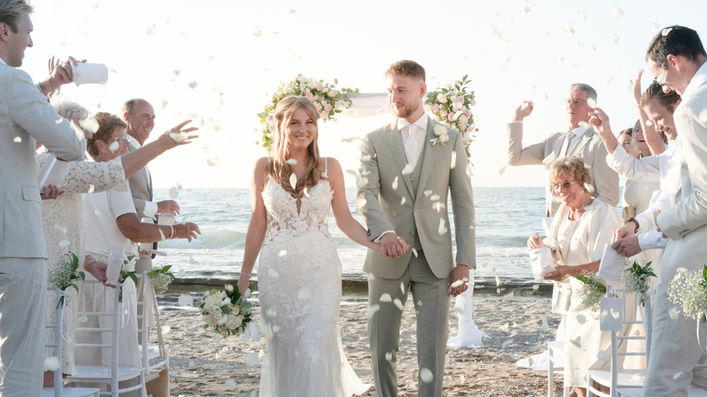 bride and groom walking through guests throwing petals beach wedding, destination wedding ceremony exit Greece, candid wedding celebration moment natural light, emotional wedding photography crowd interaction, cinematic wedding storytelling seaside ceremony, joyful couple walking together wedding day
