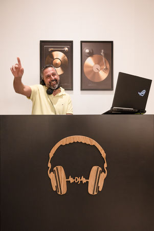 personal branding portrait of DJ performing with headphones and laptop, energetic music performance, DJ at work, expressive gesture, modern music branding image, nightlife and event atmosphere, professional DJ identity, dynamic lifestyle portrait, music producer branding, strong visual presence