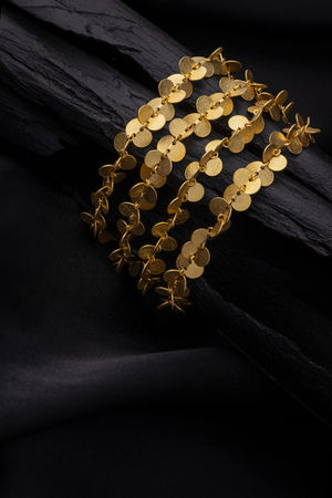 photographer based in Crete, jewelry photography with studio lighting, gold chain earrings with circular elements on dark textured background, luxury product photography for jewelry brands and e-shop, branding image for catalog and online store, φωτογράφιση κοσμημάτων στην Κρήτη για επαγγελματική προβολή και εμπορική χρήση