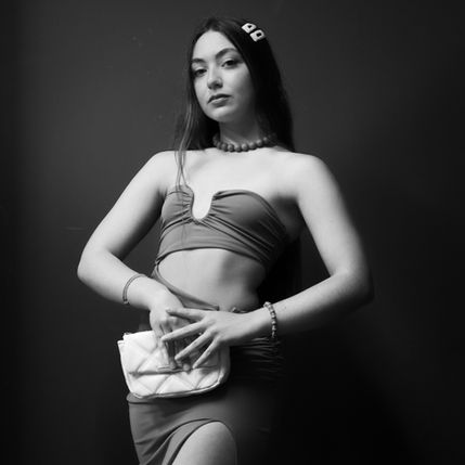 elegant woman portrait holding clutch bag, Antonis Karakonstantakis photographer, fashion inspired personal branding image, minimal black and white aesthetic, confident female pose studio background, modern elegance identity portrait, clean composition with strong presence