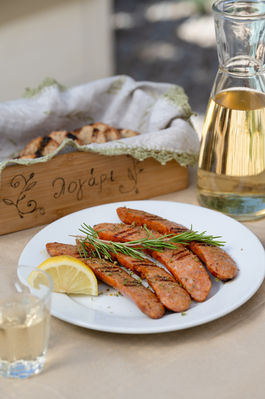 Professional commercial food photography of grilled sausages served with lemon, fresh rosemary, artisan bread, and olive oil, created for restaurant menus, hospitality branding, and food marketing.