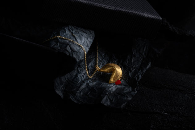 jewelry photography with studio lighting, gold fortune cookie necklace on dark textured background, φωτογράφιση κοσμημάτων για e-shop και κατάλογο, product photography for jewelry brands, luxury branding and online store presentation