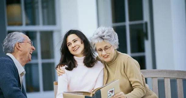 Mother hugging her daughter and laughing, with father looking-on.
