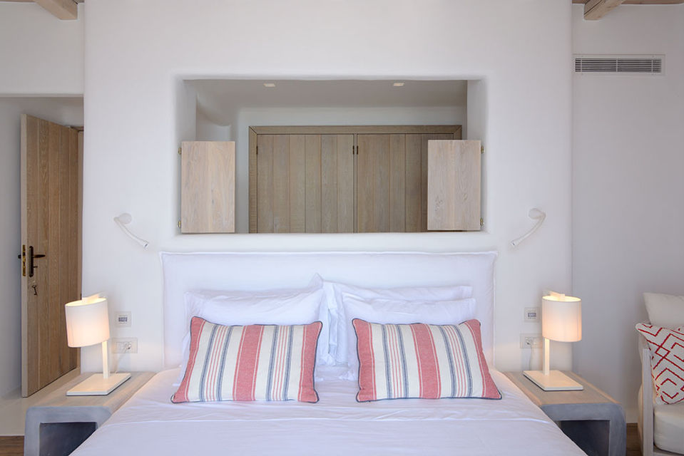 a bed with striped pillows and a mirror above it