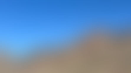 The Moon rises in the desert day on clear blue sky