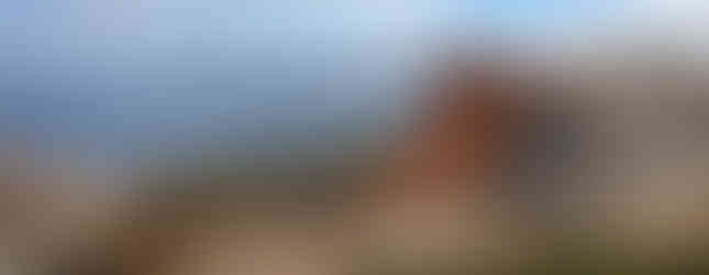 Closer view of the orange lichen on one of the formations against the backdrop of a bay.