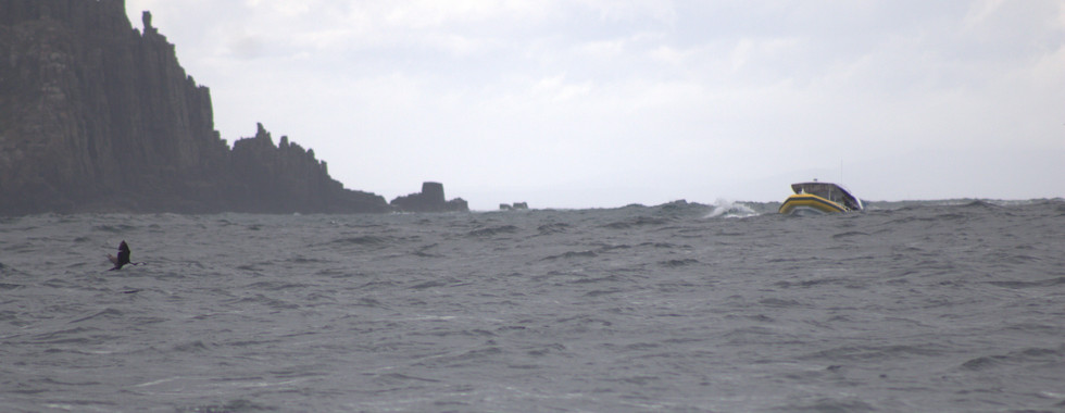 A boat navigates intense sea swell at speed among caves