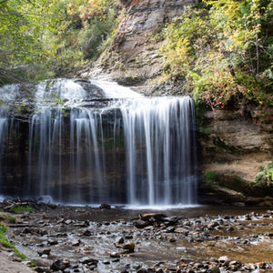 Small waterfall with surrounding greenery and rocks.