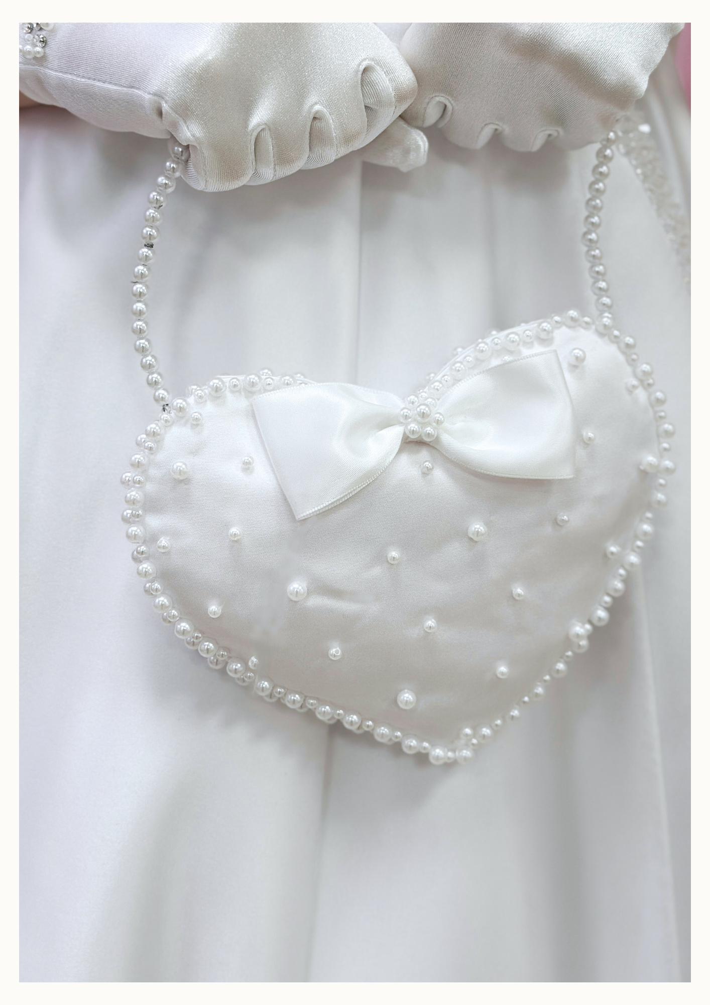 White handmade heart shaped satin communion bag with white satin bow and pearl embellishment with pearl handle
