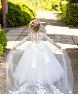 Ivory flower girl dress with lace train and satin bow at the back with lace sleeves