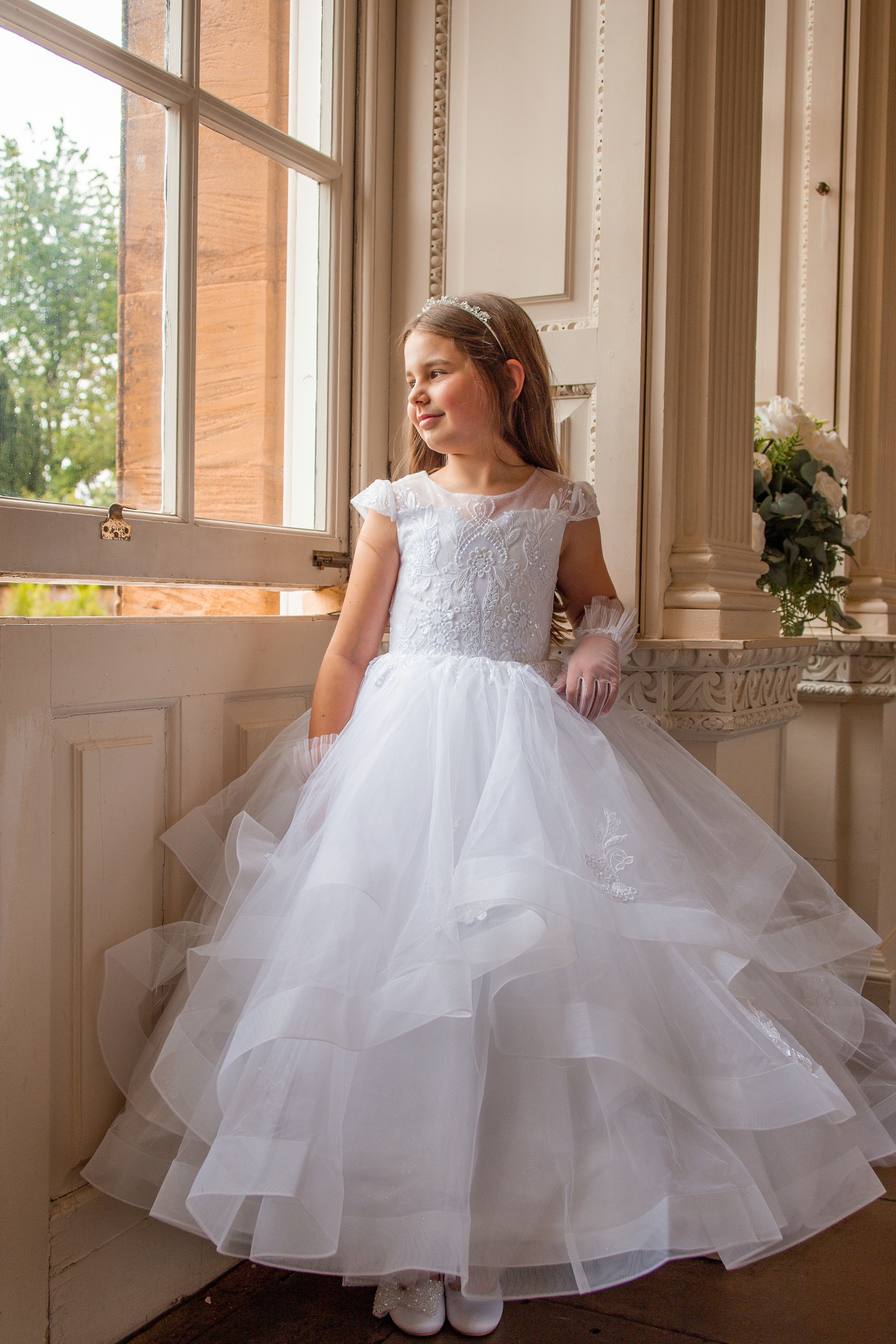 Girl wearing crystal and pearl boutique white holy communion/flower girl dress with lace and ruffle bodice