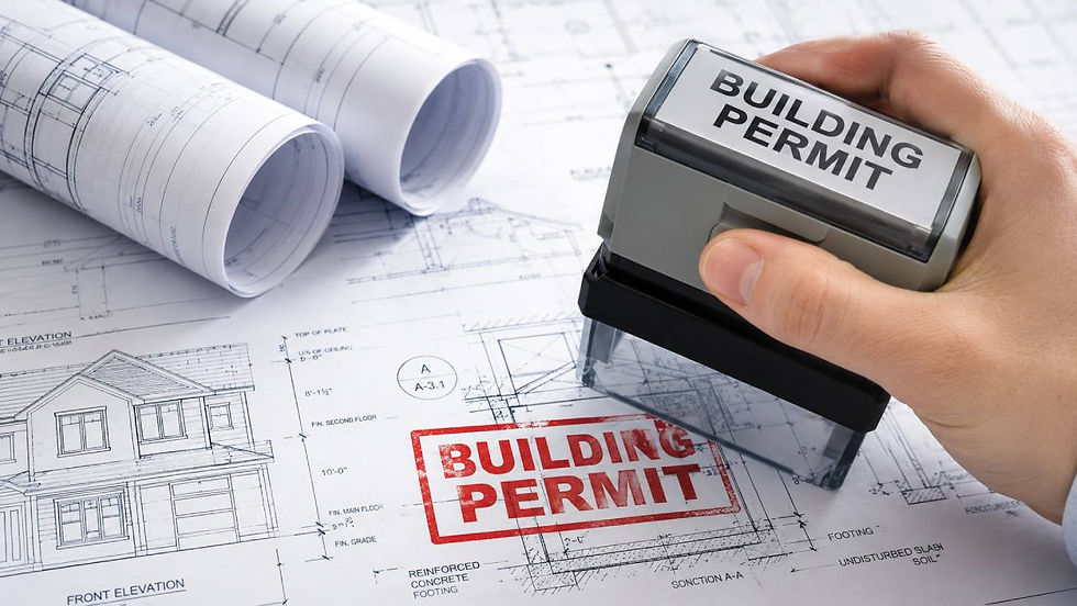 Hand stamping "BUILDING PERMIT" on architectural blueprints, featuring house designs. Two rolled-up plans in the background convey an official mood.