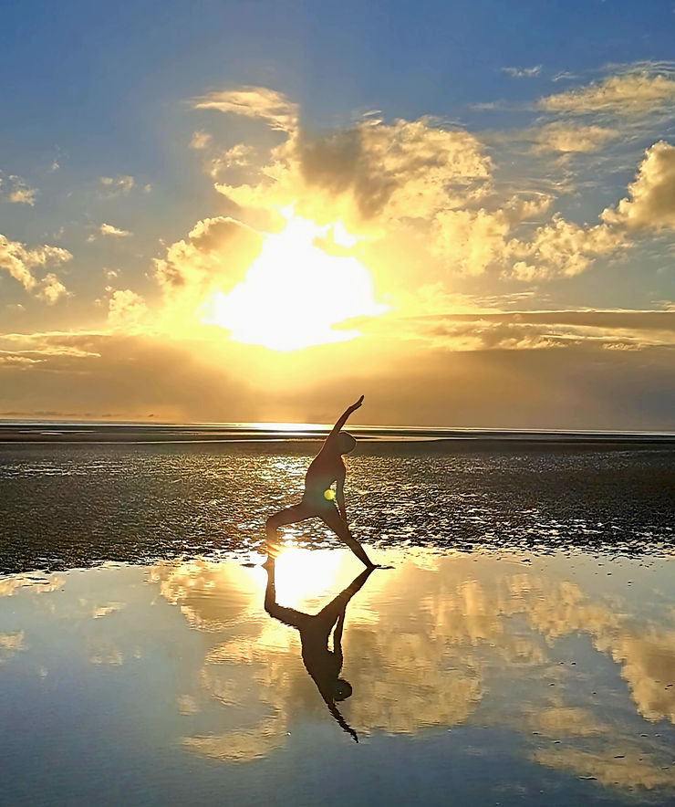 A woman practicing yoga on the beach at sunrise