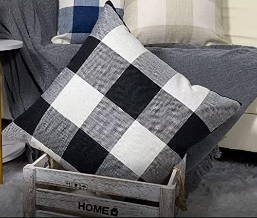 Black and white checkered pillow in a wooden crate labeled "HOME," set on a gray fluffy rug with more pillows and a blanket in the background.