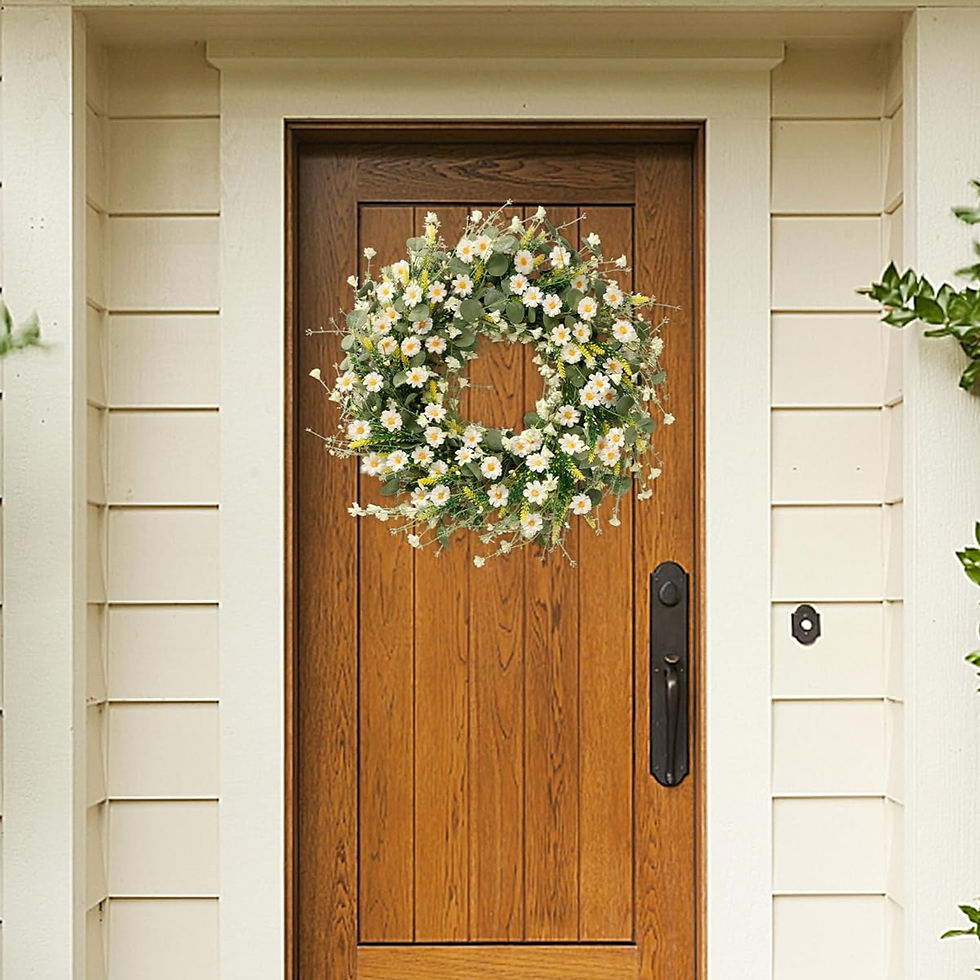 Wooden door with a floral wreath of white daisies and greenery. Cream siding in the background creates a welcoming, rustic vibe.